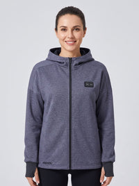 A woman wearing a grey blue zip-up heated hoodie with a black zipper.