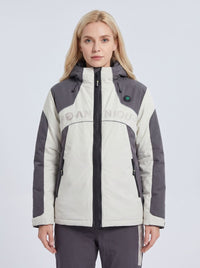 A woman modeling a color-blocked hooded heated ski jacket in off-white and dark gray, featuring a black front zipper, zippered pockets, and a subtle 'ANNIOU' logo across the chest.