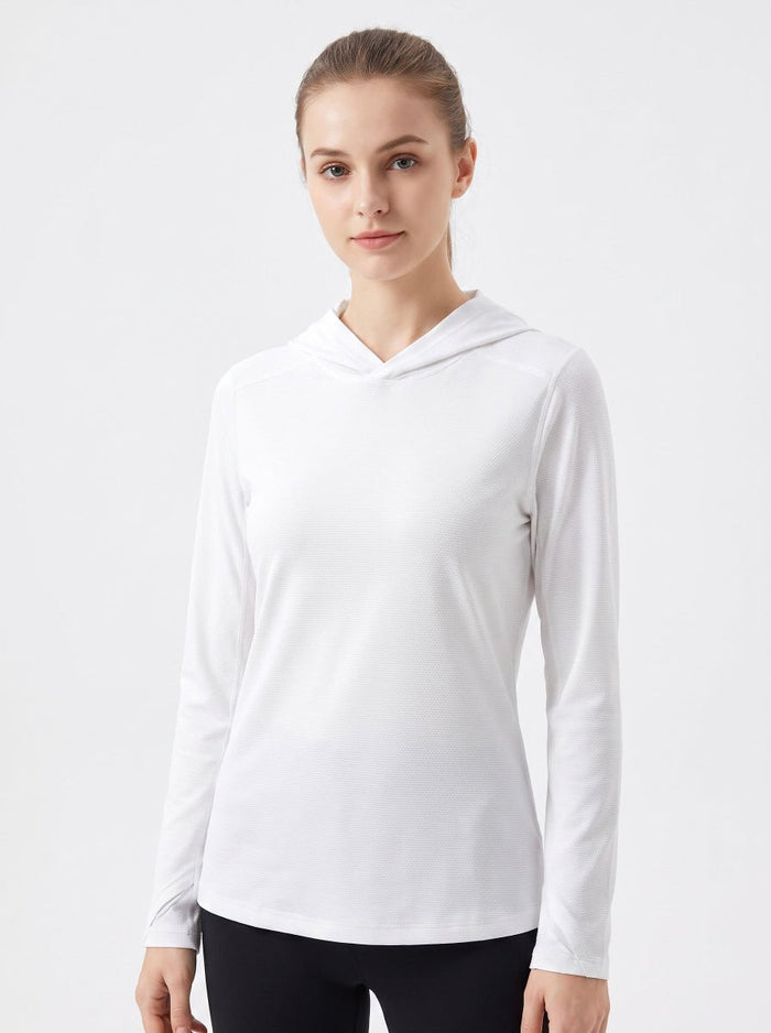 A woman wearing a white long-sleeve athletic uv hooded top, paired with black leggings, against a plain light gray studio background.