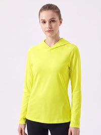 A woman wearing a bright neon yellow long-sleeve athletic uv hooded top, paired with black leggings, against a plain light gray studio background.
