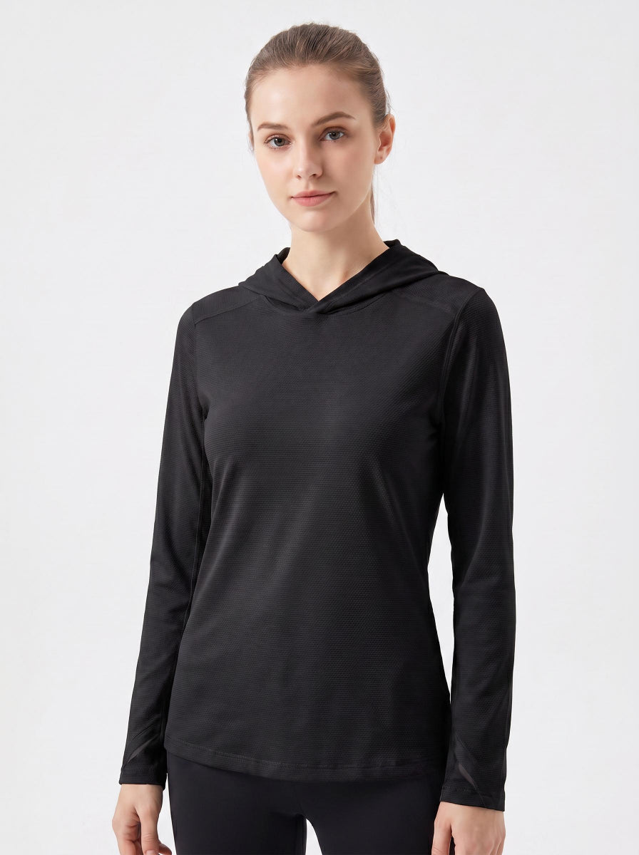 A woman modeling a black long-sleeve athletic Uv hooded top against a plain light gray studio background.